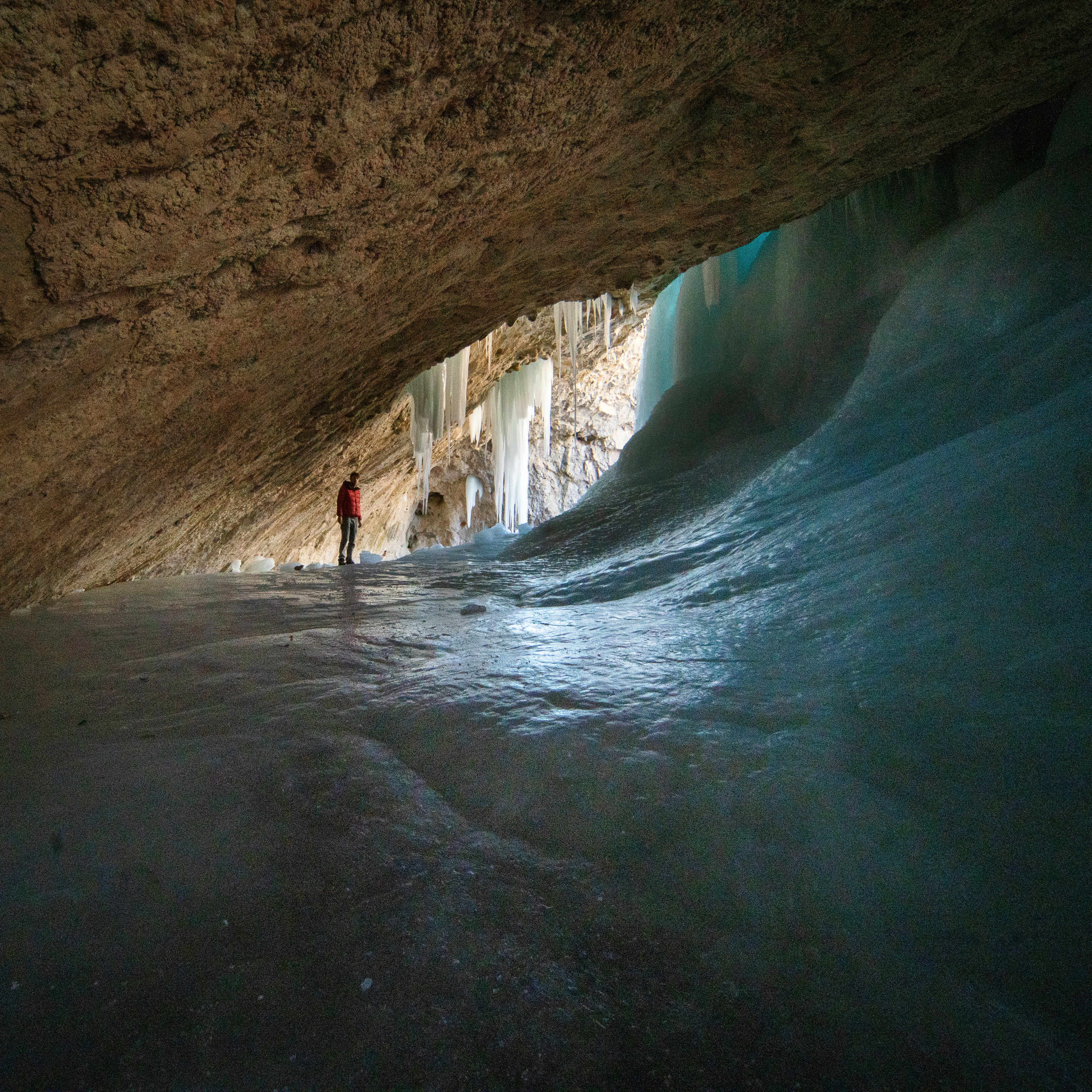 person in white shirt walking inside cave